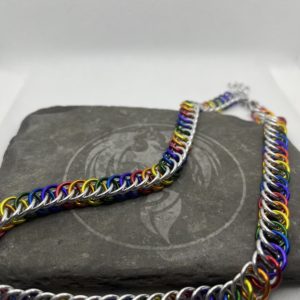 A chainmaille chain completed in the Persian 4 in 1 weave. It has alternating rings in the colors of the traditional pride flag--red, orange, yellow, green, blue, and purple. Silver rings are intermixed forming a bright backdrop to the alternating rings.