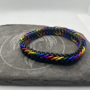 A chainmaille bracelet made with the persian 4 in 1 weave. This bracelet represents the Traditional Pride flag. It is made of black EPDM rings, and red, orange, yellow, green, blue, and purple anodized aluminium rings.