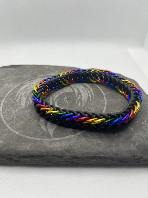 A chainmaille bracelet made with the persian 4 in 1 weave. This bracelet represents the Traditional Pride flag. It is made of black EPDM rings, and red, orange, yellow, green, blue, and purple anodized aluminium rings.