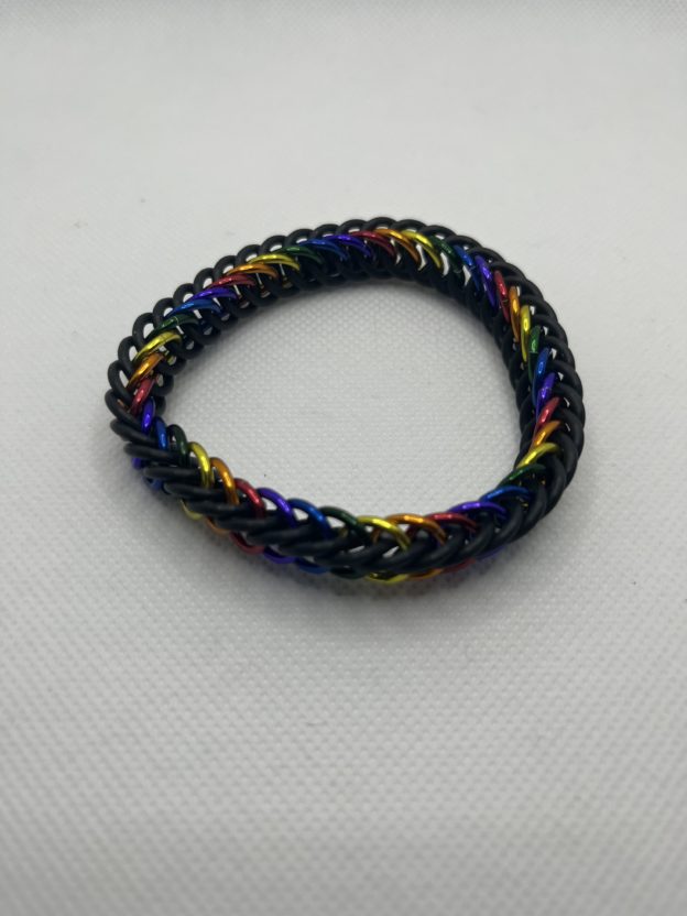 A chainmaille bracelet made with the persian 4 in 1 weave. This bracelet represents the Traditional Pride flag. It is made of black EPDM rings, and red, orange, yellow, green, blue, and purple anodized aluminium rings.