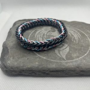 A chainmaille bracelet made with the persian 4 in 1 weave. This bracelet represents the Transgender Pride flag. It is made of black EPDM rings, and pink, lightblue, and silver anodized aluminium rings.