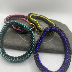 Four chainmaille bracelets created in the Persian 4 in 1 weave made with both anodized aluminum rings and EPDM rubber rings. All of the EPDM rings are black. The four bracelets are in colors of yellow, pink, sea green, and purple.