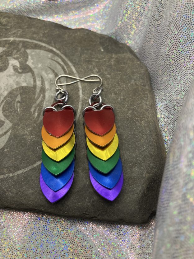 Scalemail earrings with overlapping scales forming a straight down pattern. These earrings are six scales long, approximately 2 and one half inches, and have colors representing the traditional pride flag--red, orange, yellow, green, blue, and purple.